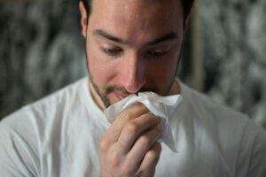 Man with a cold, blowing his nose with tissue