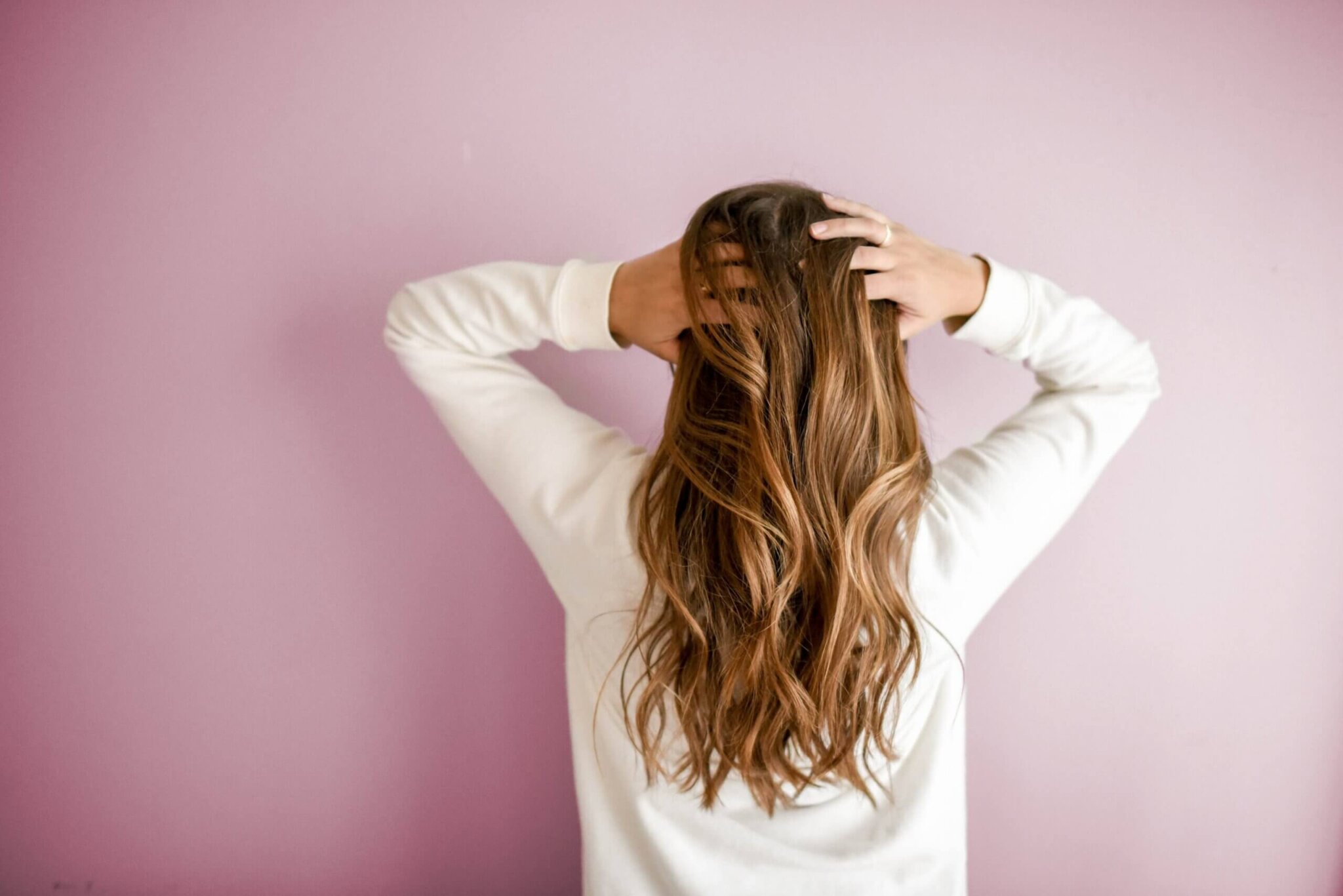 Woman with her back to camera running hands through her hair