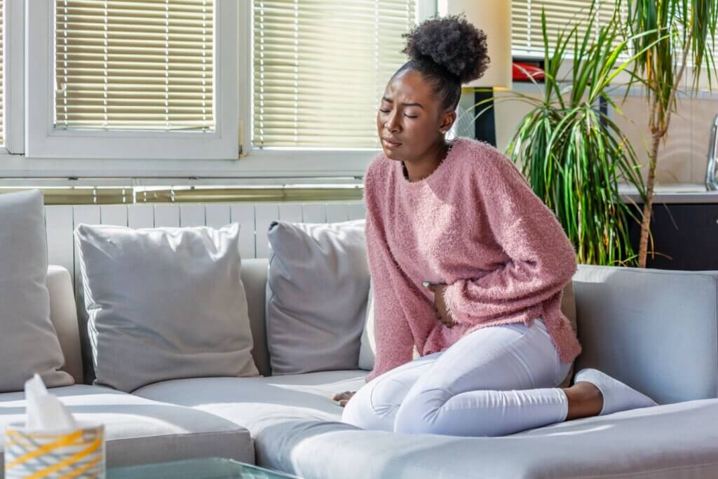 Woman sitting on coach clenching her stomach