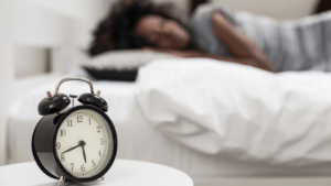 clock on the nightstand, woman sleeping in background