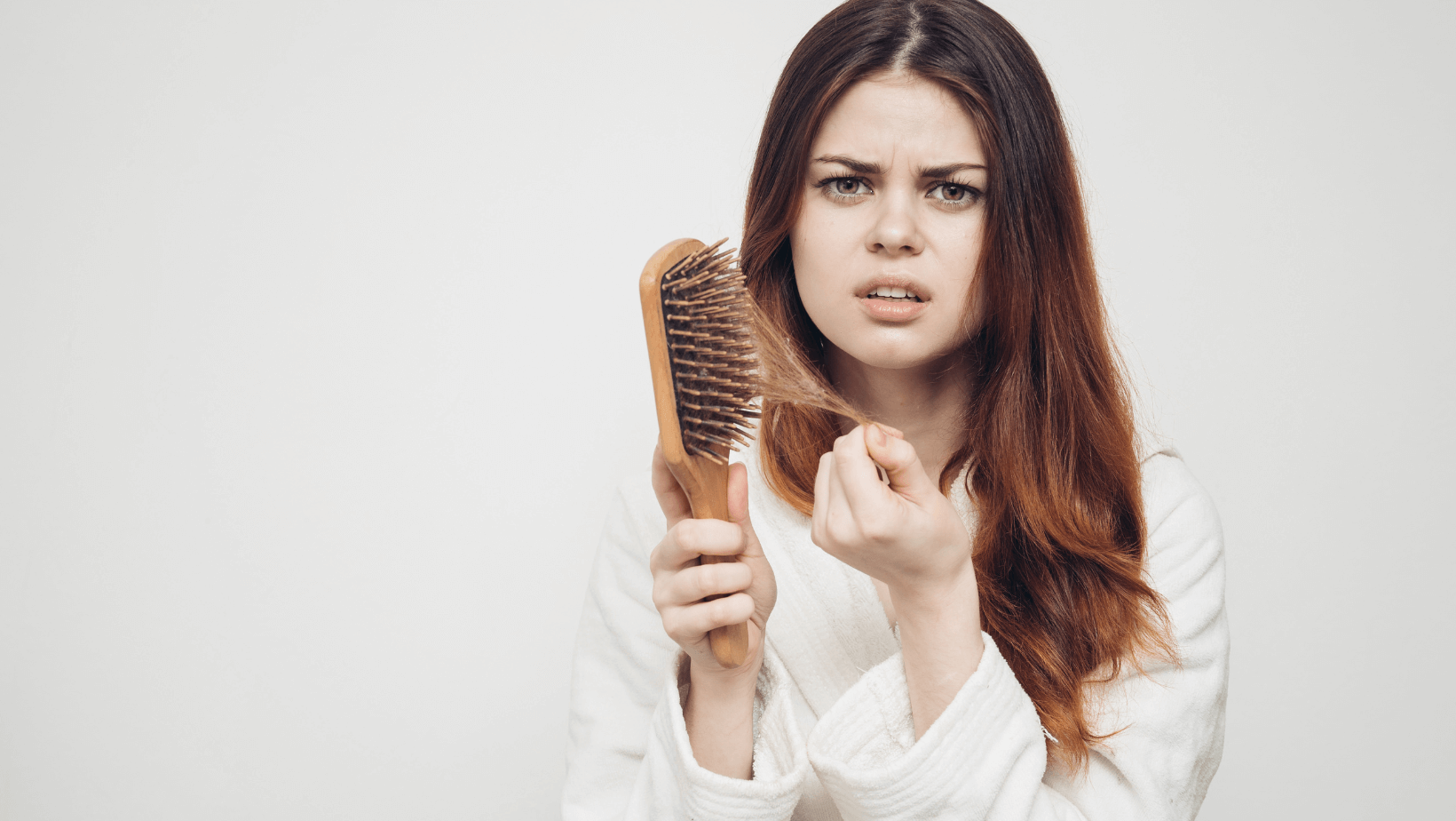 woman looking distressed holding hair brush full of hair