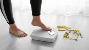 woman stepping onto a scale with measuring tape on the floor