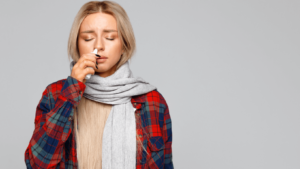 woman dressed for winter, wearing a scarf using nasal spray