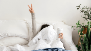 Women with outstretched arm flashing victory symbol from bed