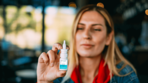 Woman smiling holding bottle of enovid nasal spray