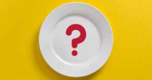 white dinner plate on yellow background, Red question mark in middle of plate