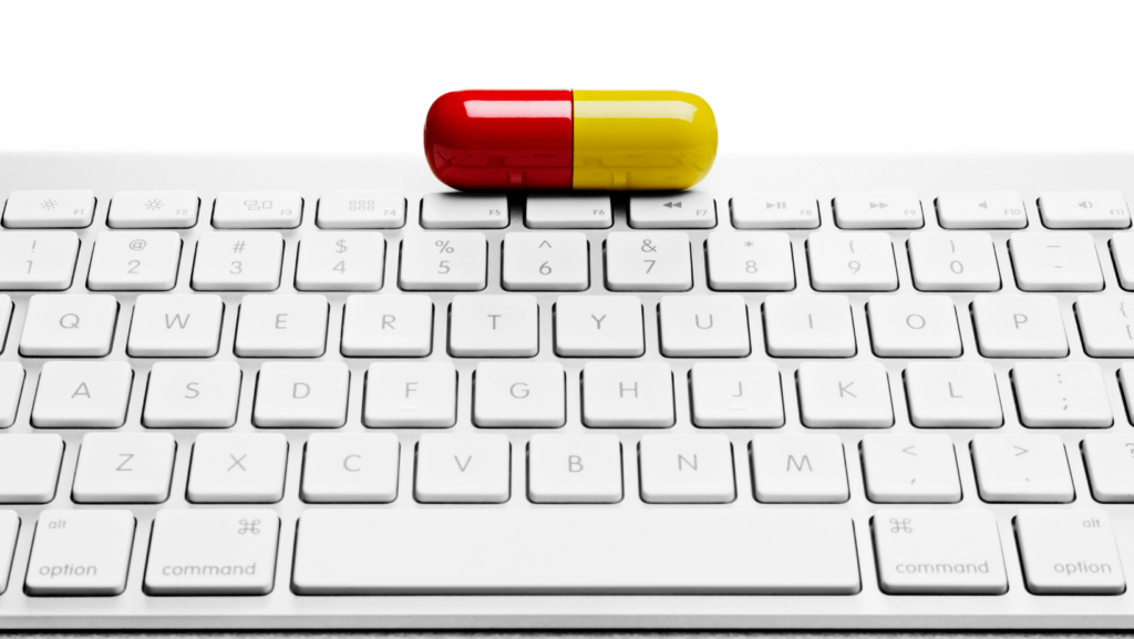 yellow and red pill resting on top of computer keyboard