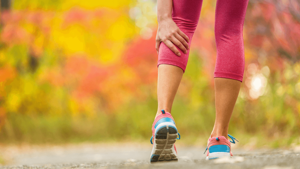 woman walking and reaching down to soothe muscle cramp