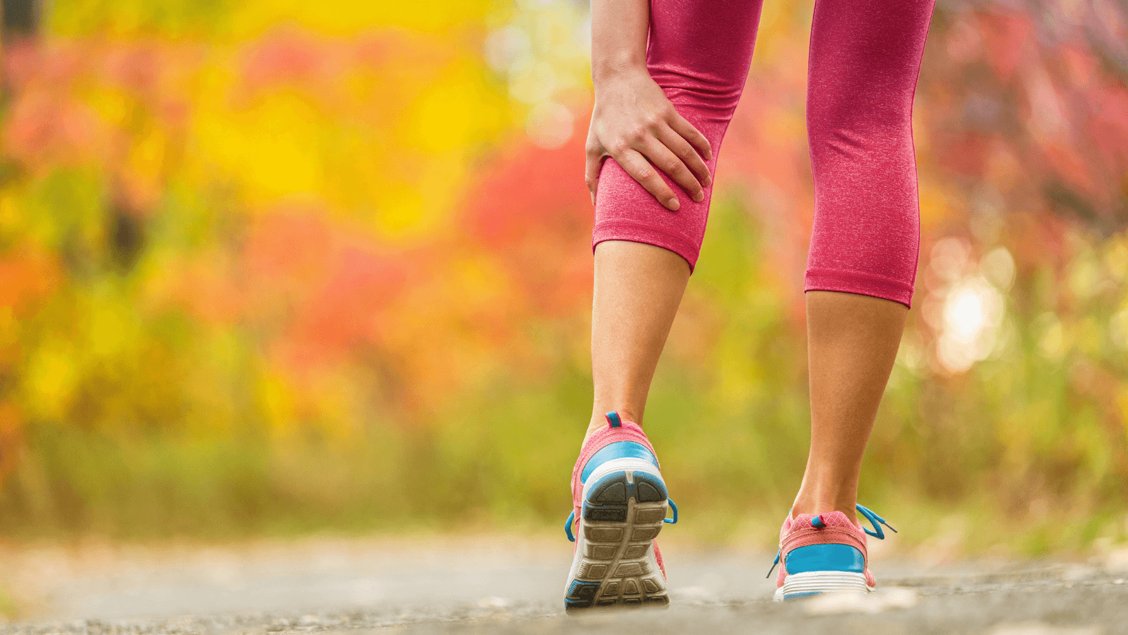 woman walking and reaching down to soothe muscle cramp