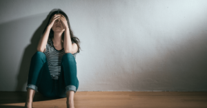 despondent woman sitting with her hands over her face