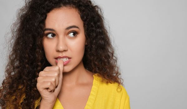 Woman Biting Her Nails on Grey Background. Spac