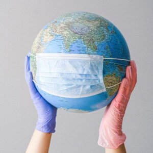 Hands With Latex Gloves Holding a Globe with a Face Mask