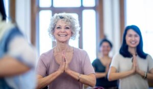 Older woman smiles while doing yoga