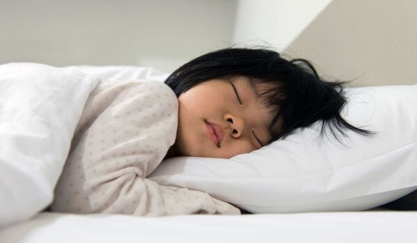 child sleeping on white bed