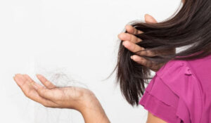 woman worried about Hair loss , young asian female holds loss hair on a white background