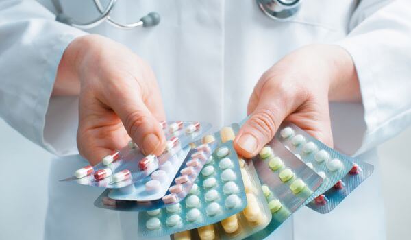 Doctor holding out several packs of a variety of pills