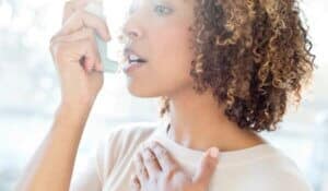 Young woman treating asthma with inhaler