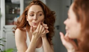 Young Woman Popping Acne On Face