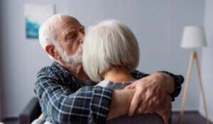 senior man hugging and kissing wife, suffering from alzheimer's disease