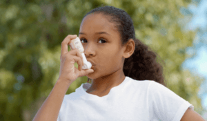 Young girl using asthma inhaler