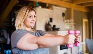 Attractive overweight woman at home holding dumbbells, working out.