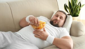 Man laying on couch Holding a Bowl of Chips on the Sofa