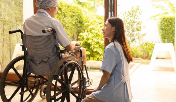 Young Nurse with Patient in a Wheelchair at Home