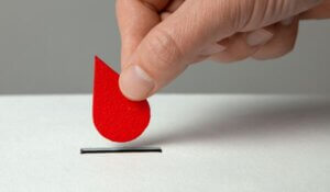 Blood donor. Man puts drop of blood in the piggy bank as donation.