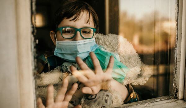 Covid - child with mask behind window