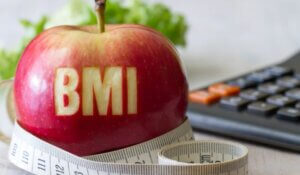 Red apple with text BMI, measuring tape and calculator, diet and healthy weight concept