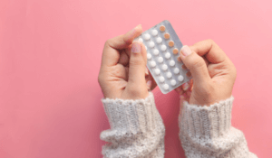 Women Hand Holding Birth Control Pills on