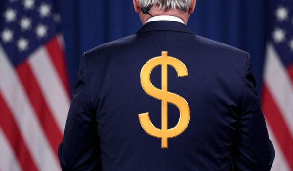 US politician standing with his back to crowd with dollar sign on his back
