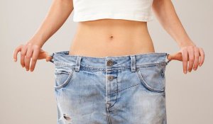 woman holding her jeans which are too large due to weight loss