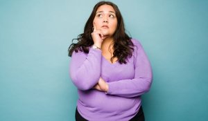 Pensive, full-bodied woman thinking about Excessive Body Mass Definitions and Facts