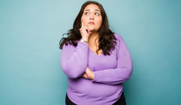 Pensive, full-bodied woman thinking about Excessive Body Mass Definitions and Facts