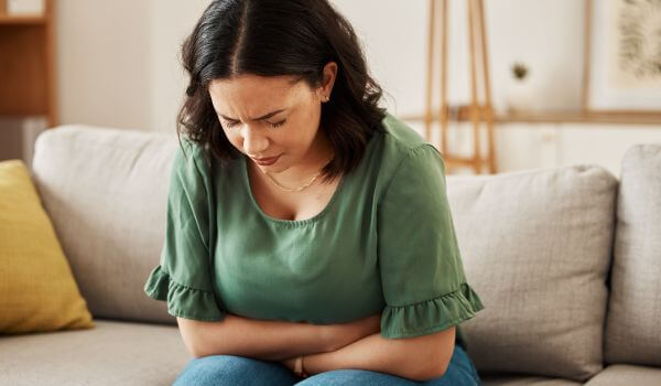 Woman on sofa struggling with IBS pain
