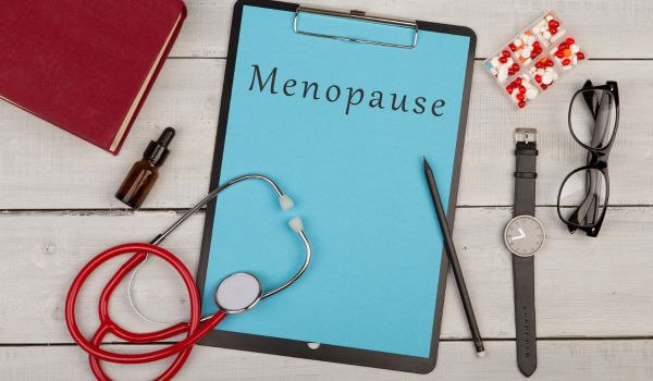 clipboard with text Menopause, stethoscope, pills, book, watch and eyeglasses