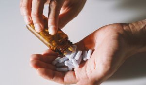 Hand emptying a bottle of pills into palm of hand