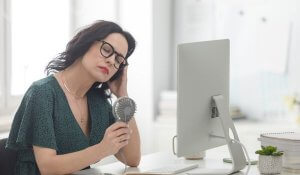 Mature woman suffering hot flash in the office