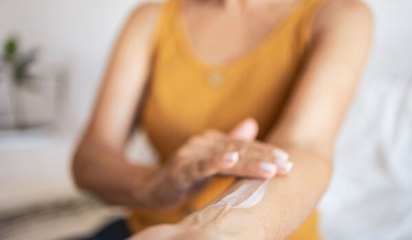 Woman rubbing hormone replacement therapy on her skin