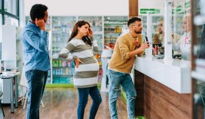 Men and a pregnant woman are frustrated as they queue in a pharmacy 