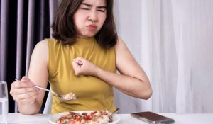 Woman eating with acid reflux and sulfur burps from a GLP-1