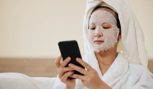 Woman wearing facemask researching how skincare marketing is unregulated