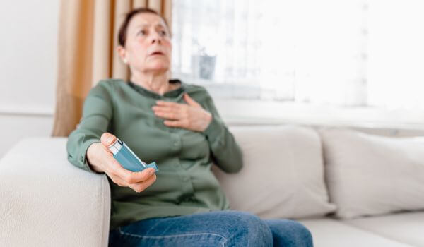 Older woman with severe asthma is out of breath and using an asthma pump